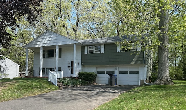 bi-level home with covered porch, an attached garage, driveway, and a front yard