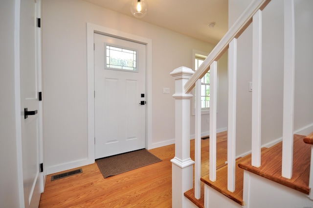 entryway with stairway, a healthy amount of sunlight, light wood-type flooring, and visible vents