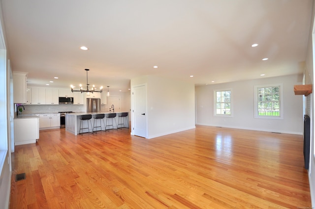 unfurnished living room featuring an inviting chandelier, recessed lighting, light wood finished floors, and a fireplace