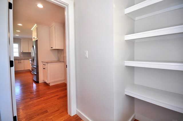 corridor featuring baseboards, recessed lighting, and wood finished floors