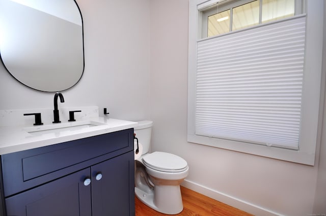 bathroom featuring toilet, baseboards, wood finished floors, and vanity