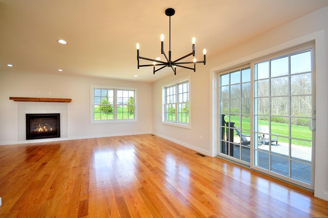 unfurnished living room featuring light wood-style floors, baseboards, recessed lighting, and a chandelier