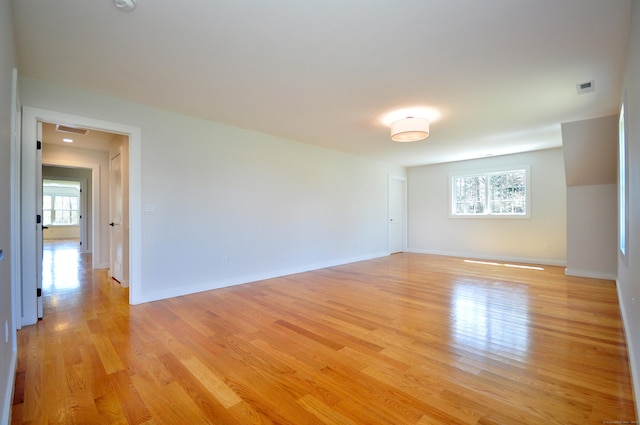 unfurnished room featuring visible vents, light wood finished floors, and baseboards