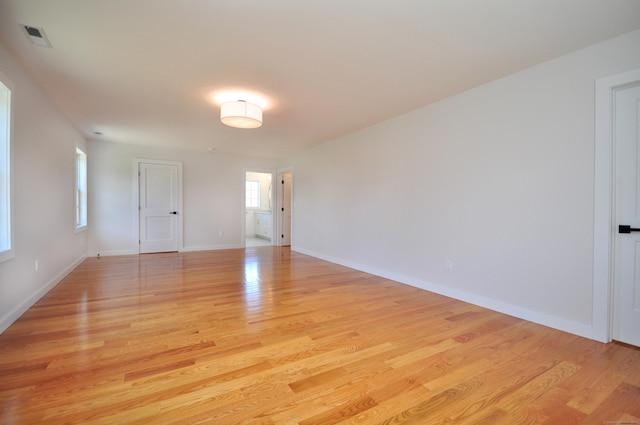 empty room with baseboards, visible vents, and light wood-style floors