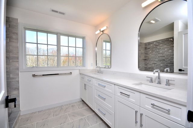 bathroom featuring a sink, a healthy amount of sunlight, tiled shower, and visible vents