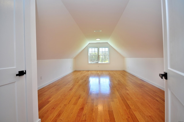 additional living space featuring baseboards, visible vents, light wood finished floors, and lofted ceiling