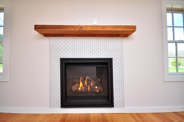 interior details featuring baseboards, a warm lit fireplace, and wood finished floors