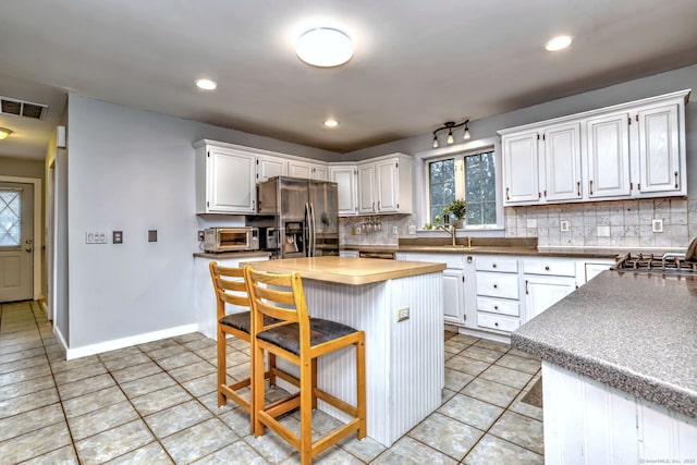 104 S St, Morris, CT 06763 - kitchen featuring refrigerator with ice dispenser, visible vents, tasteful backsplash, and white cabinetry