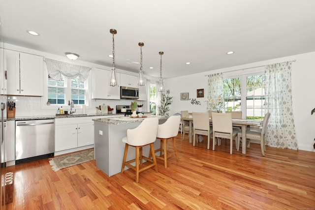 26 Greenwood Dr, Prospect, CT 06712 - kitchen featuring appliances with stainless steel finishes, a sink, white cabinetry, light wood-type flooring, and a kitchen bar