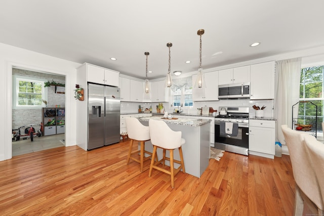 26 Greenwood Dr, Prospect, CT 06712 - kitchen with a center island, white cabinets, a breakfast bar, stainless steel appliances, and light wood-style flooring
