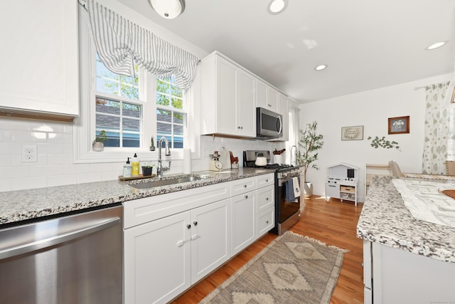 26 Greenwood Dr, Prospect, CT 06712 - kitchen with white cabinets, light stone counters, appliances with stainless steel finishes, a sink, and tasteful backsplash