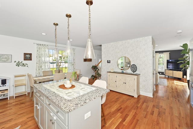 26 Greenwood Dr, Prospect, CT 06712 - kitchen featuring a kitchen breakfast bar, a kitchen island, light stone countertops, white cabinetry, and light wood-style flooring