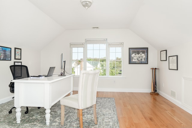 office area with baseboards, lofted ceiling, light wood-style flooring, and visible vents