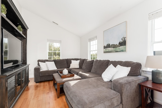 living area with vaulted ceiling, a healthy amount of sunlight, and light wood-style flooring