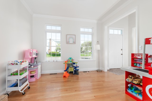 recreation room with crown molding, light wood-style flooring, baseboards, and visible vents
