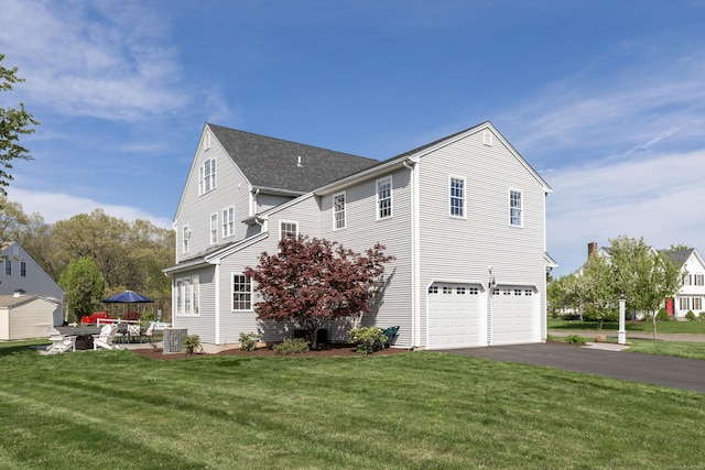 view of side of home with a garage, central air condition unit, a yard, and driveway