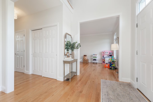 foyer featuring crown molding, light wood-style flooring, plenty of natural light, and baseboards