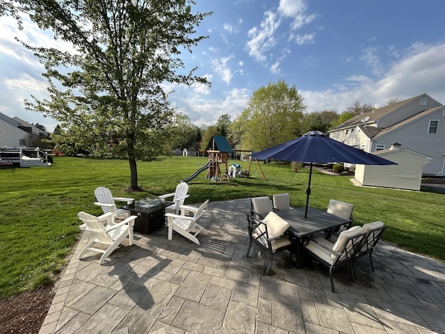 view of patio with a playground, an outdoor fire pit, and outdoor dining space