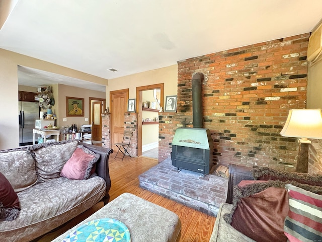 living area with baseboards, wood finished floors, and a wood stove