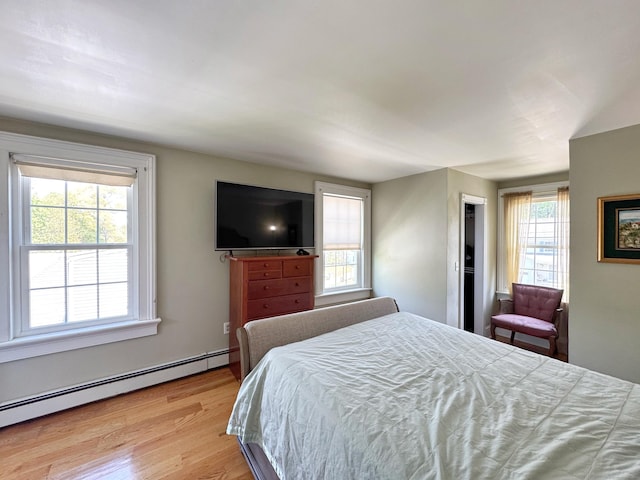 bedroom with light wood-type flooring and a baseboard radiator