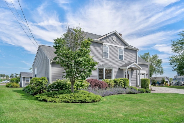 view of home's exterior featuring roof with shingles, a chimney, a yard, and gravel driveway