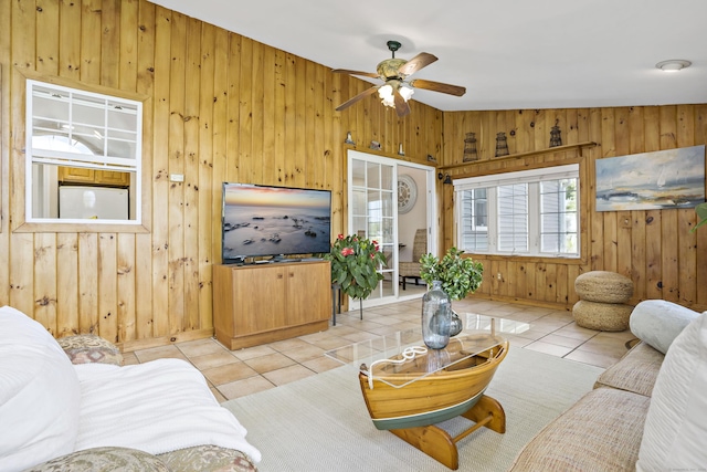 tiled living room with a ceiling fan and wood walls
