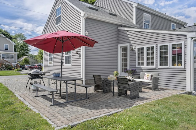 rear view of house with a shingled roof and a patio area