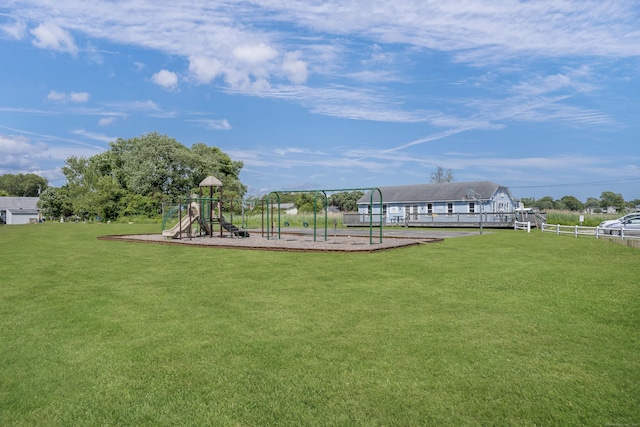 view of property's community featuring a lawn, fence, and playground community