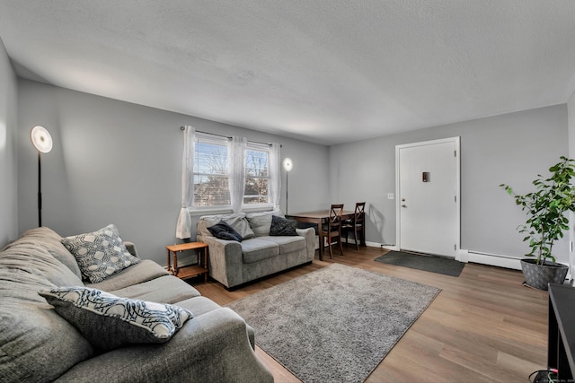 living room featuring baseboards, a baseboard radiator, a textured ceiling, and wood finished floors