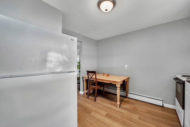 dining area with baseboards, light wood finished floors, and baseboard heating
