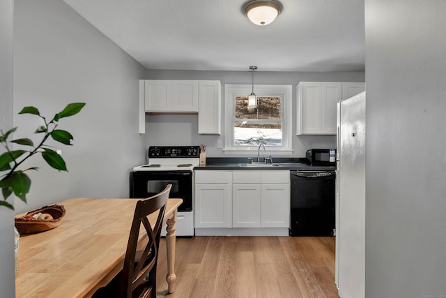 kitchen featuring dark countertops, a sink, white cabinets, black appliances, and light wood finished floors