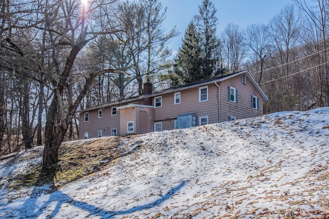 snow covered rear of property with a chimney