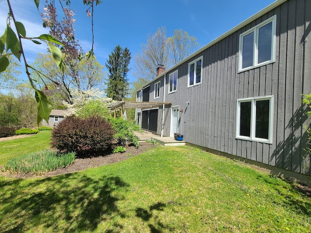 back of property with a chimney, a pergola, and a lawn