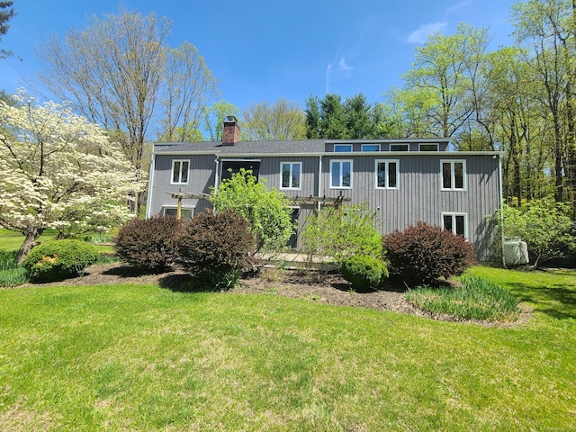 view of front facade with a chimney, a front yard, and board and batten siding