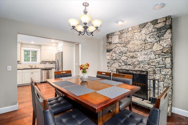 dining room with a fireplace, dark wood-style flooring, baseboards, and a chandelier