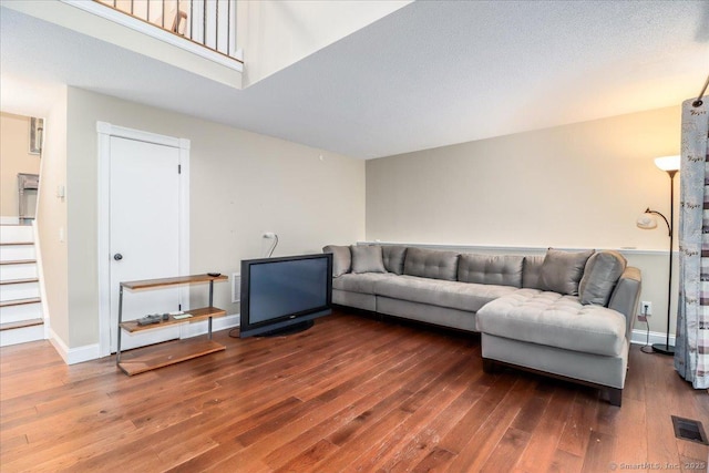living area with visible vents, baseboards, hardwood / wood-style floors, and stairs