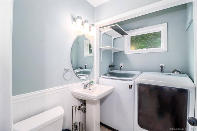 bathroom with washing machine and clothes dryer, wainscoting, and toilet