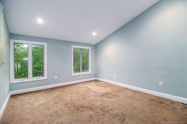 unfurnished room featuring carpet, vaulted ceiling, and baseboards