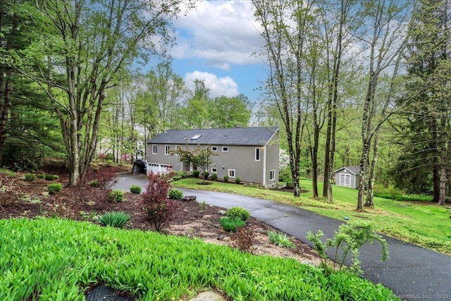 bi-level home with driveway, an outdoor structure, a shed, and a front lawn