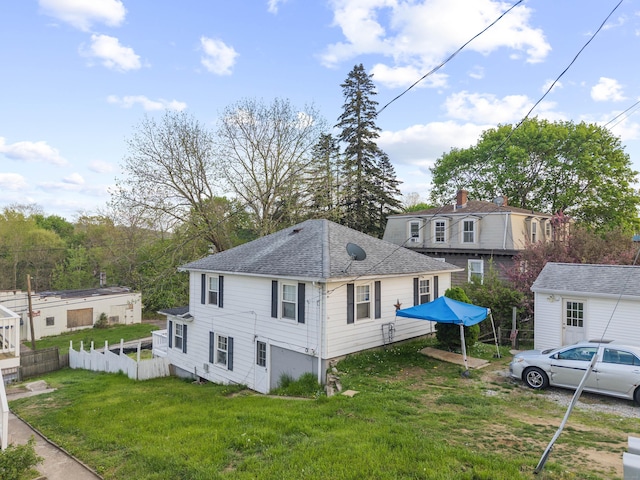exterior space featuring a lawn, fence, and a shingled roof