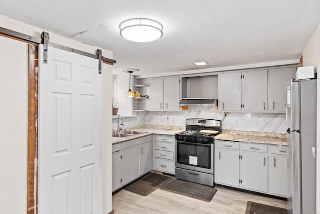 kitchen with open shelves, a barn door, a sink, under cabinet range hood, and stainless steel appliances