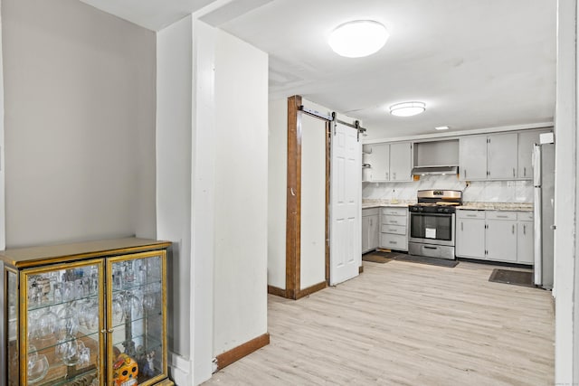 kitchen with open shelves, a barn door, light countertops, stainless steel appliances, and baseboards