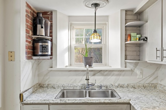 kitchen featuring a sink, open shelves, pendant lighting, and white cabinetry