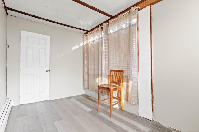 unfurnished room with a baseboard radiator and wood finished floors