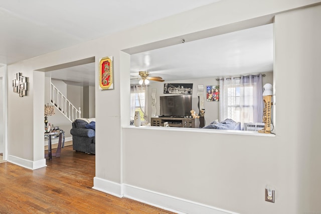 living area featuring a ceiling fan, stairs, wood finished floors, and a wealth of natural light