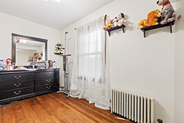 bedroom with radiator and wood finished floors