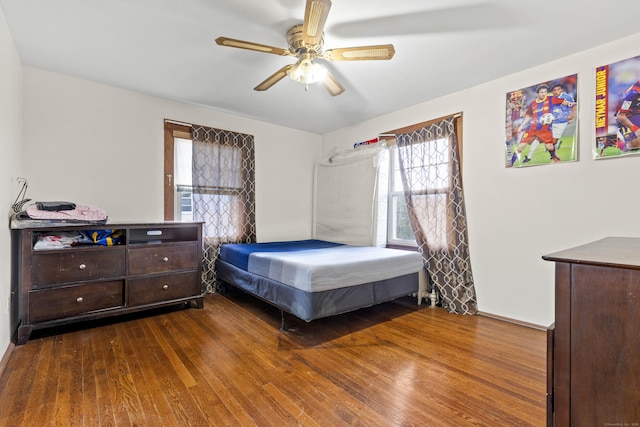 bedroom with a ceiling fan, multiple windows, and wood finished floors