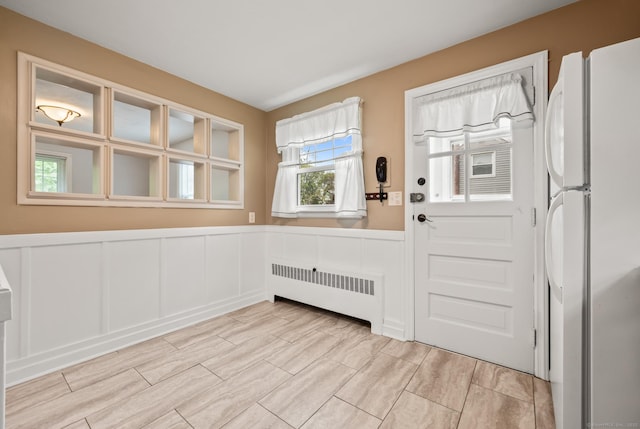 doorway to outside featuring wood tiled floor, radiator, a decorative wall, and wainscoting
