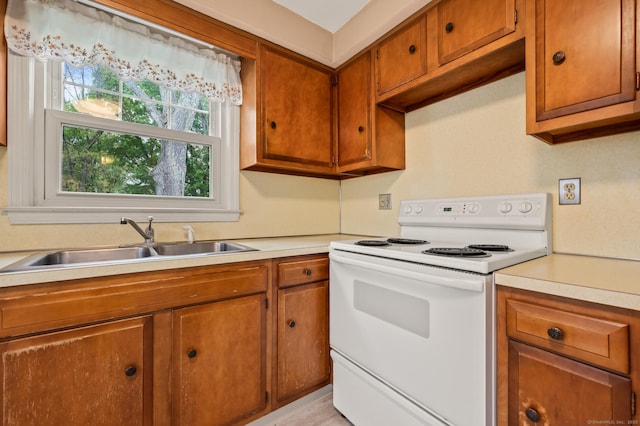 kitchen featuring a sink, light countertops, white range with electric stovetop, and brown cabinets