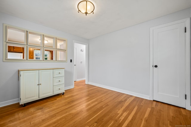 unfurnished dining area featuring light wood-type flooring and baseboards